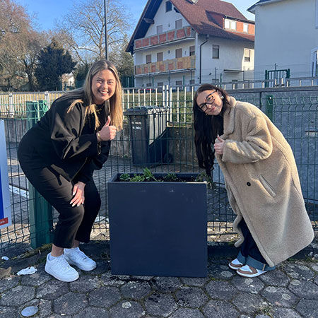 Tatkräftiger Einsatz vor Ort – Zwei Auszubildende präsentieren die erste Pflanzaktionen direkt an der Geschäftsstelle.