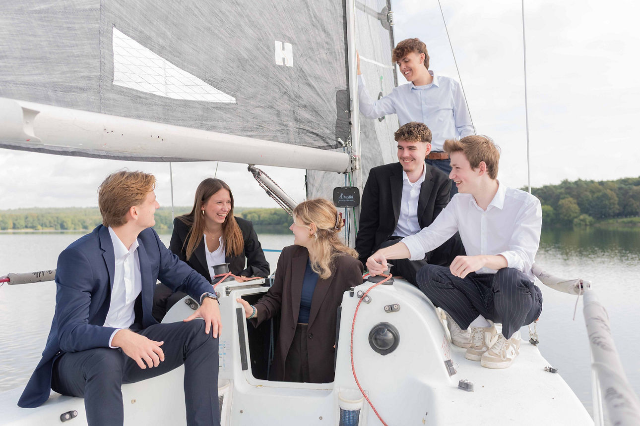 Zwei junge Frauen und Vier junge Männer sitzen auf ein Segelboot mit schicken Anzug