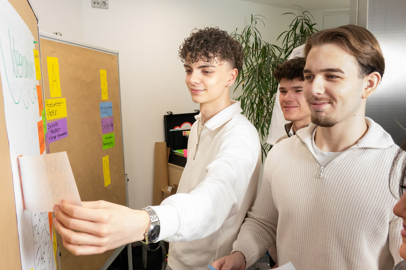 Drei junge Männer arbeiten an einer Metaplanwand