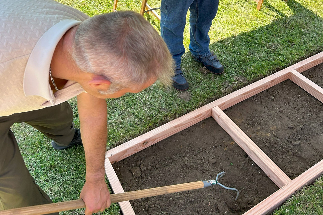 Eine Person gräbt die Erde im Barfußpfad um.