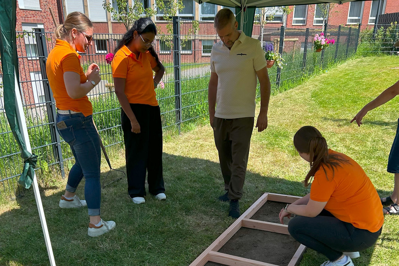 Vier Personen stehen um den Barfußpfad herum und beraten sich.