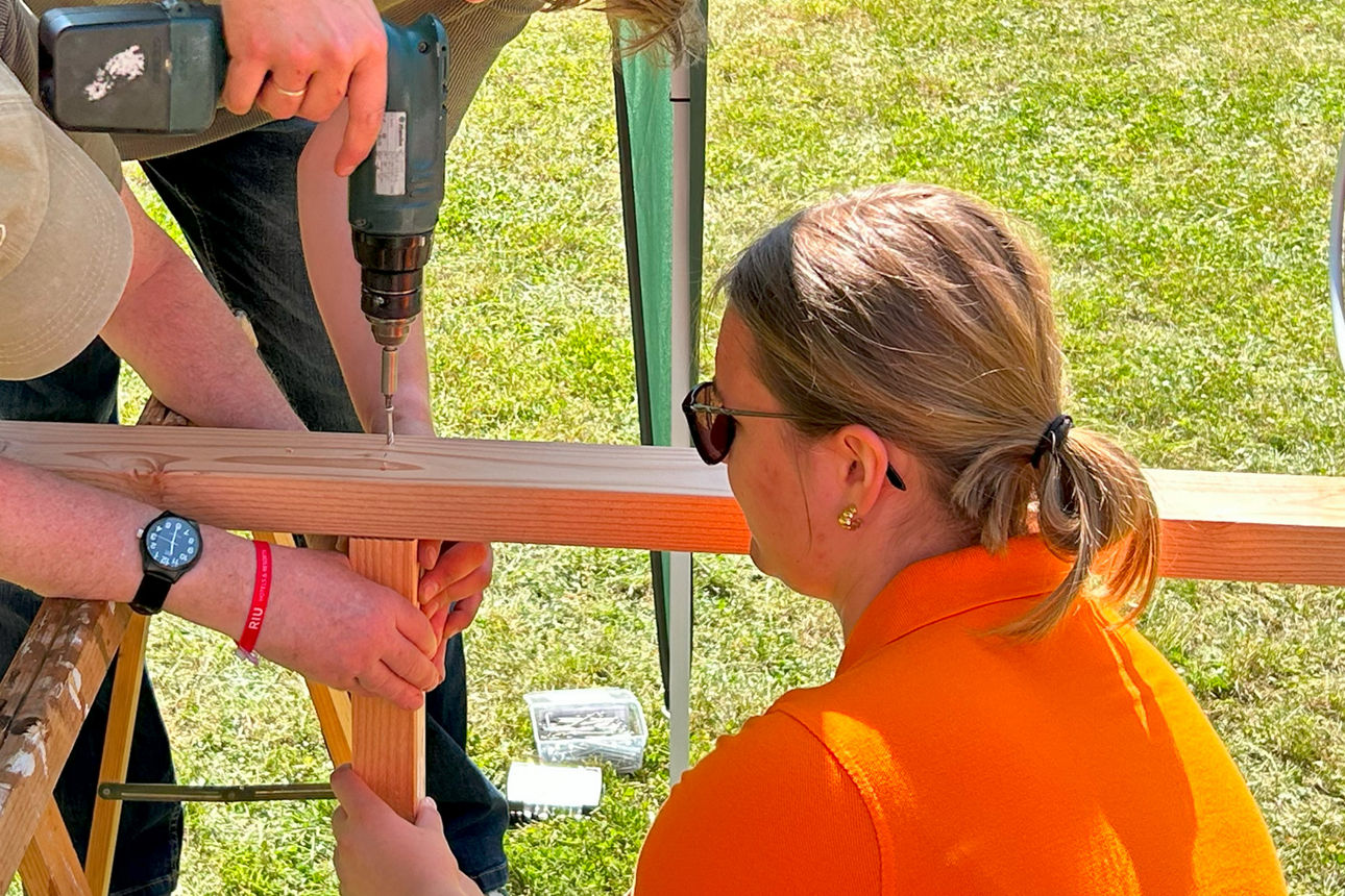 Zwei Personen halten Teile des Grundgerüstes während eine dritte diese zusammen schraubt.