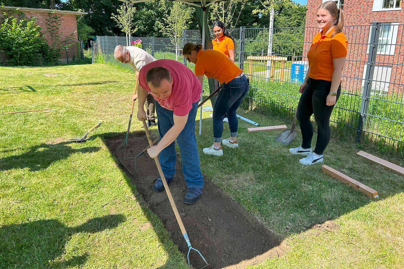 Drei Personen heben die Grundfläche des Barfußpfades aus. Zwei weitere stehen dahinter. 