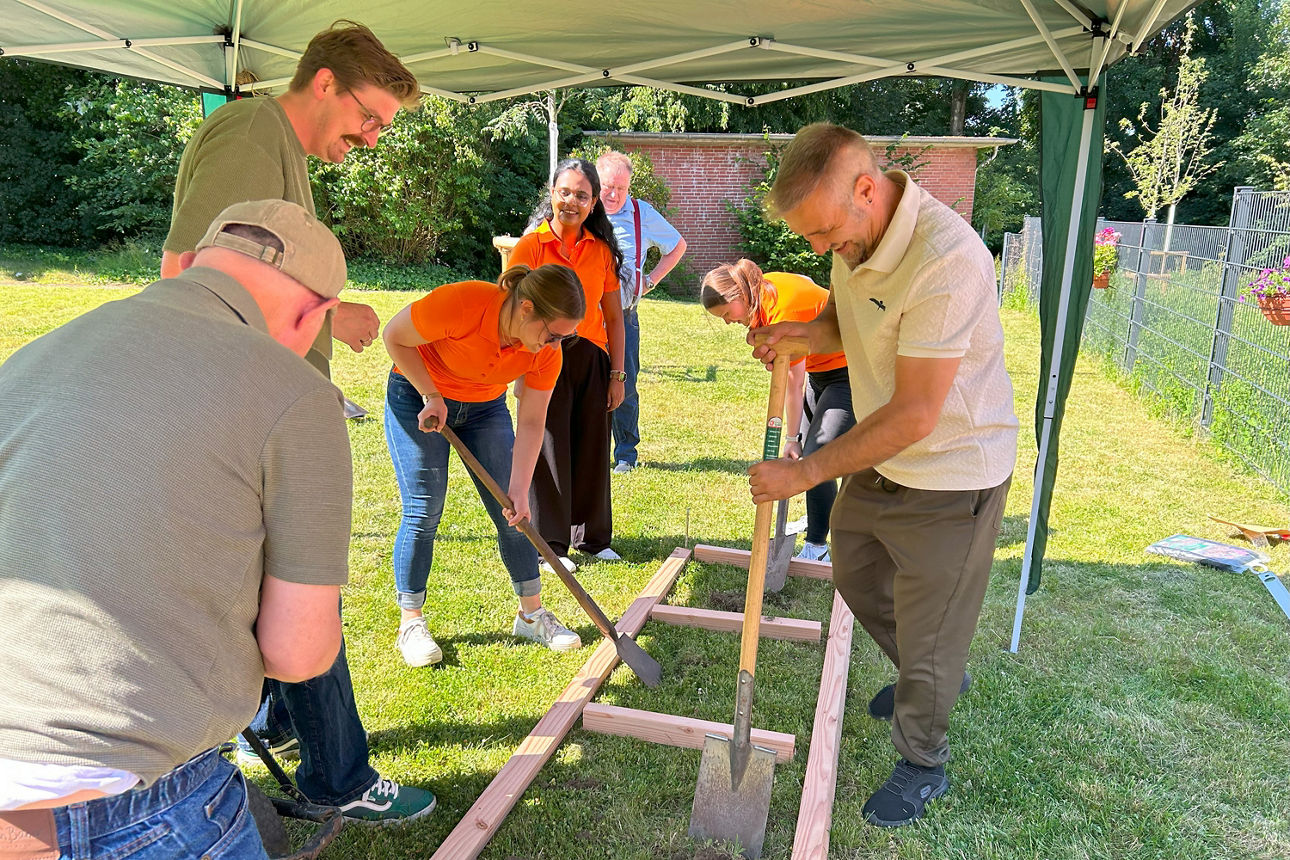 Eine Gruppe Personen schaufelt die Felder für den Barfußpfad frei.