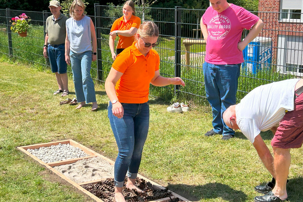 Eine Frau Testet läuft im Barfußpfad neben ihr stehen 5 weitere Personen.