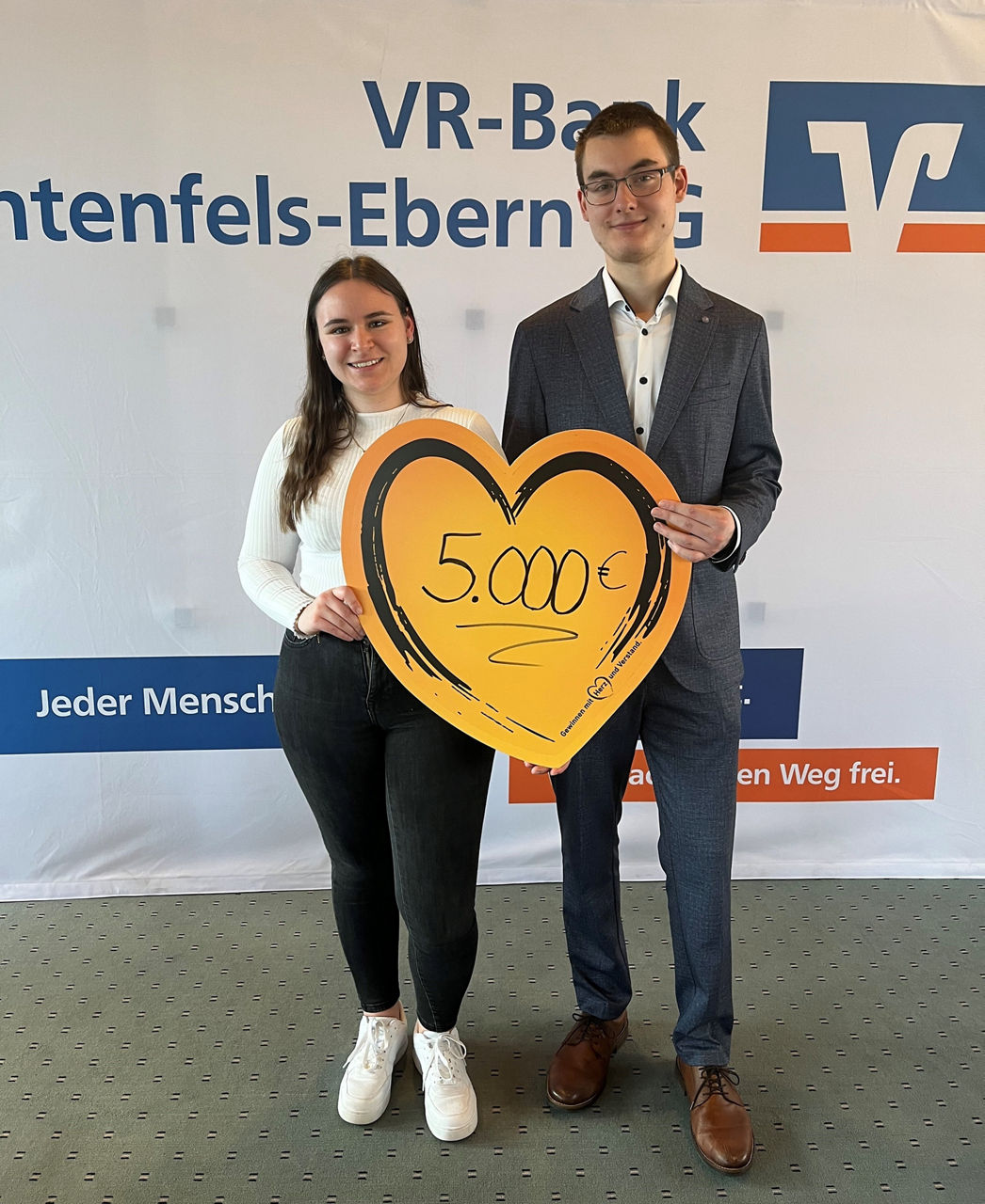 Eine Frau und ein Mann halten ein Spendenübergabeherz hoch