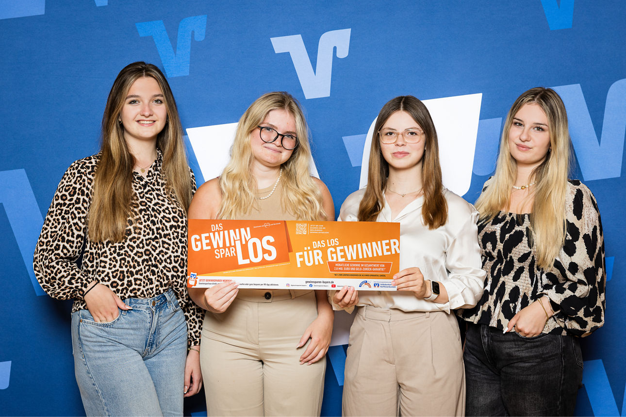 Vier Frauen halten ein Gewinnsparlos in die Kamera