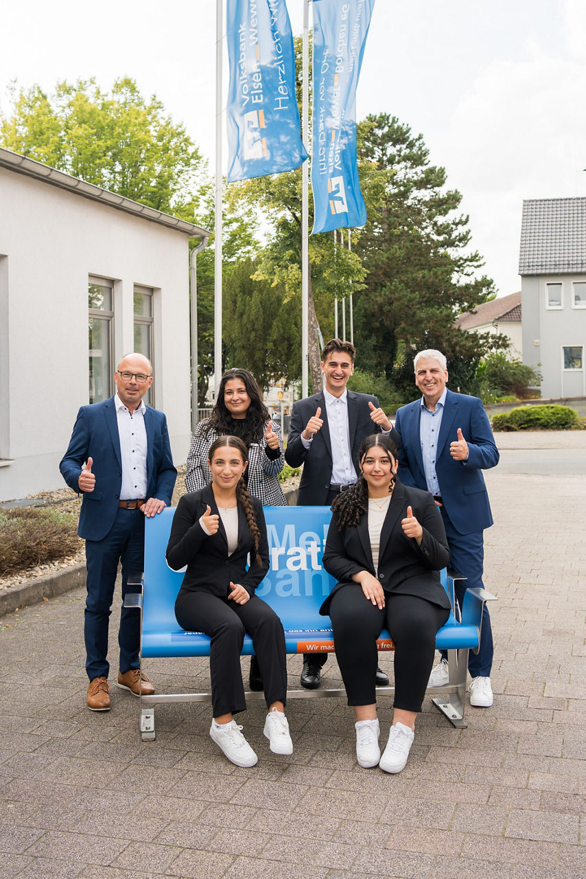 Eine Gruppe junger Menschen sitzend und stehend um eine blauen Bank versammelt.