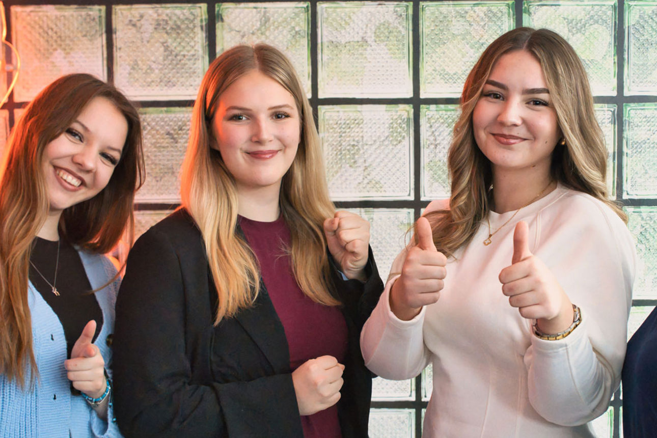 Vier Auszubildende lächeln und zeigen die Daumen nach oben