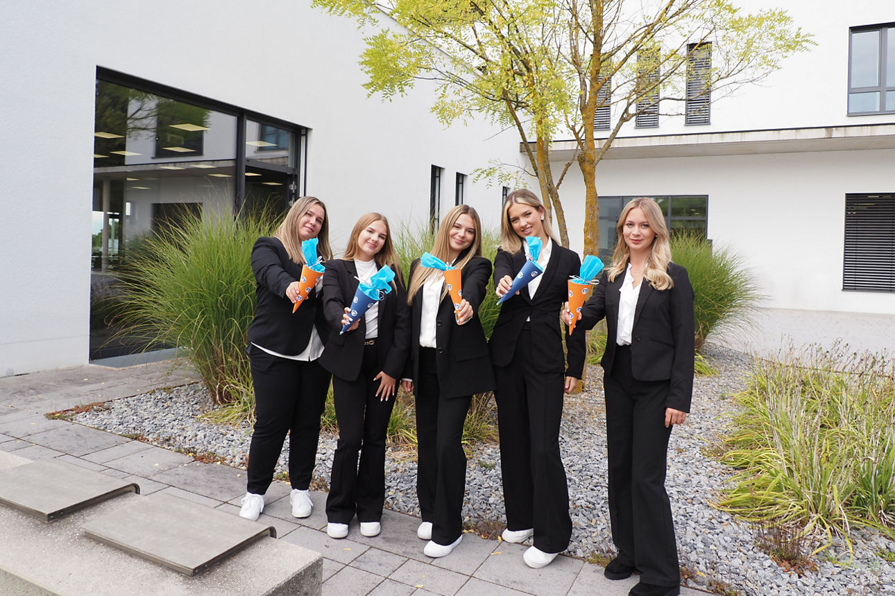 fünf Auszubildende stehen mit Mini-Schultüten lächelnd nebeneinander