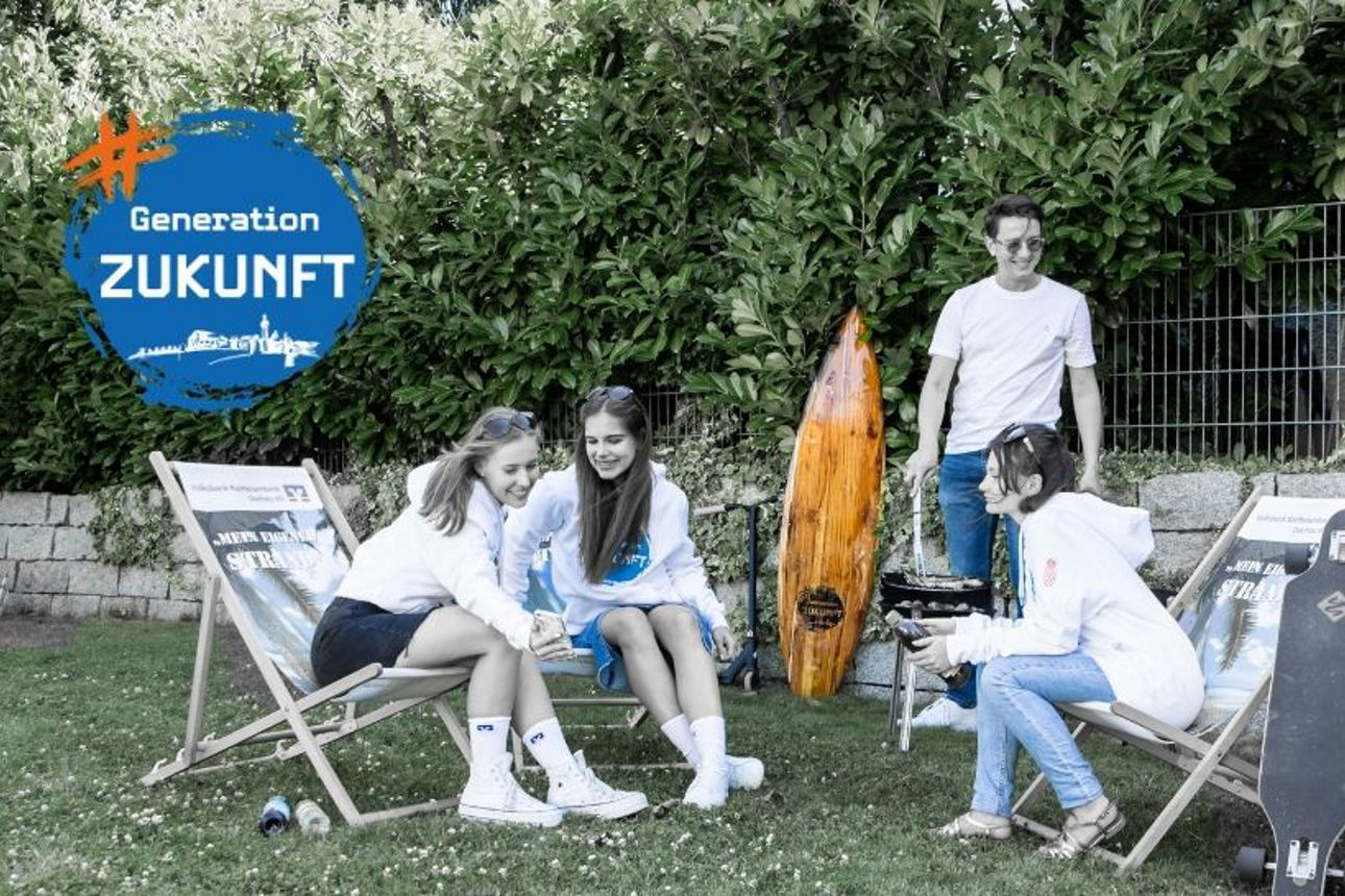 Junge Menschen sitzen im Garten und grillen.