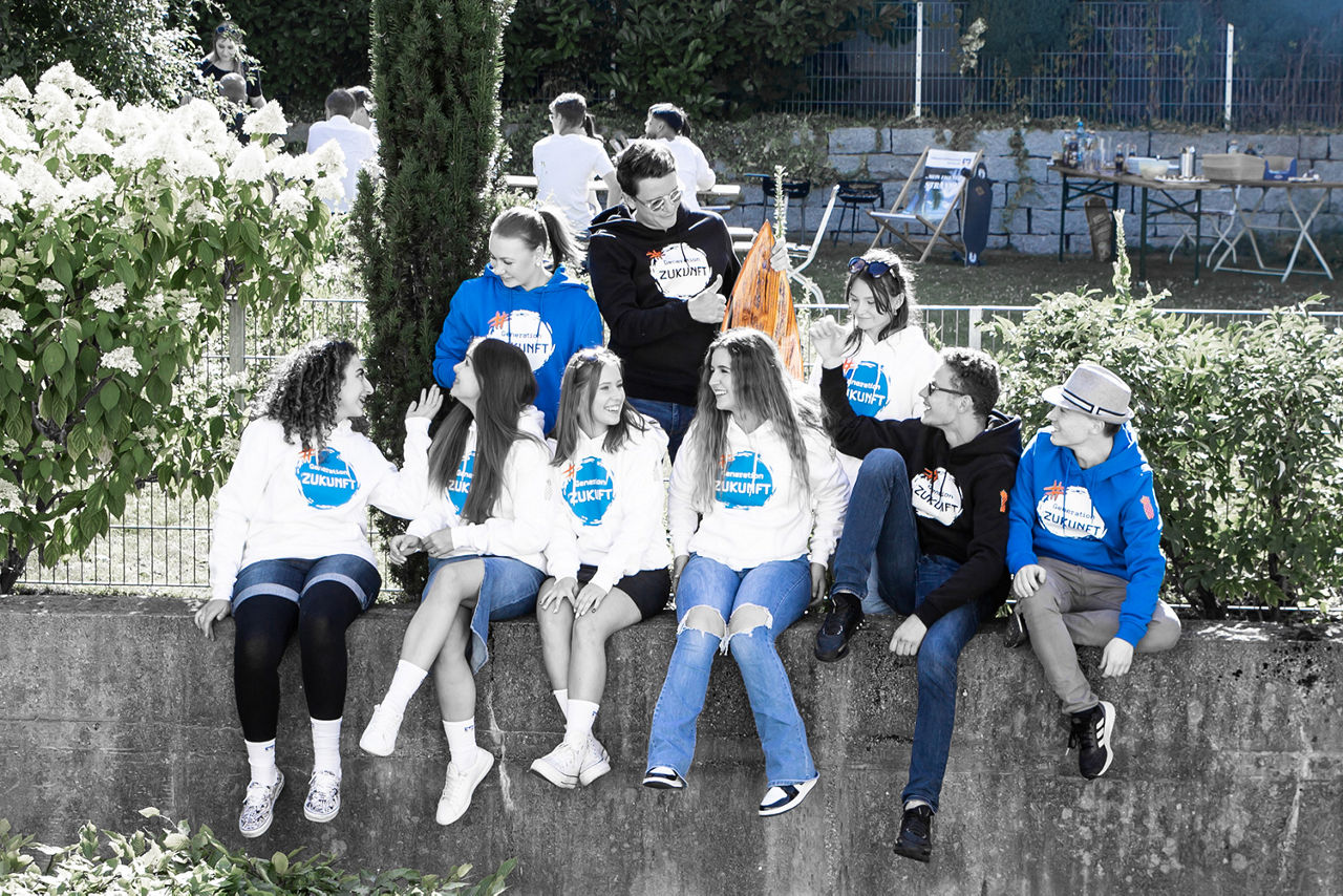 Jugendliche sitzen zusammen auf einer Mauer