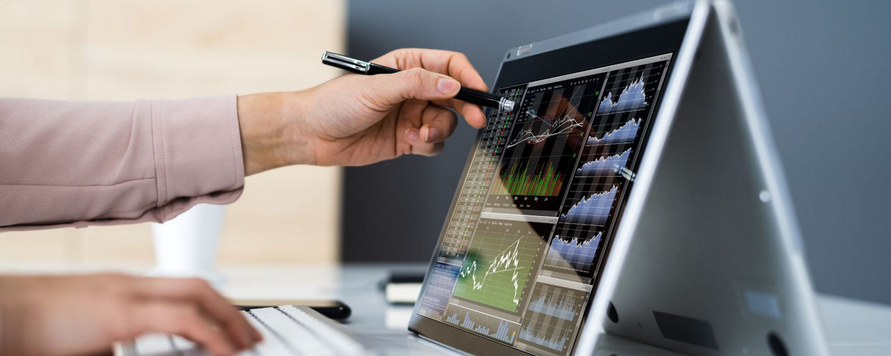 Hand zeigt auf Laptop mit Börsennachrichten