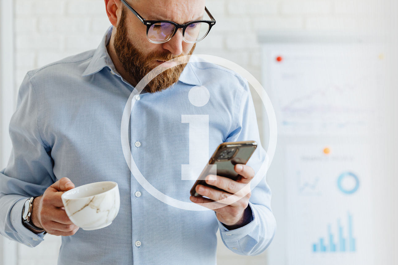 Ein Mann mit Hemd hält Tasse und Smartphone, steht vor Tafel mit bunten Diagrammen und Grafiken.