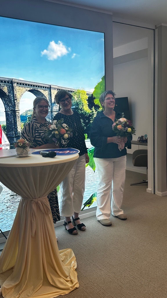 J. Steinhoff, I. Straßburg und I. Beermann mit Blumensträußen in der Herdecker Filiale nach der Lesung