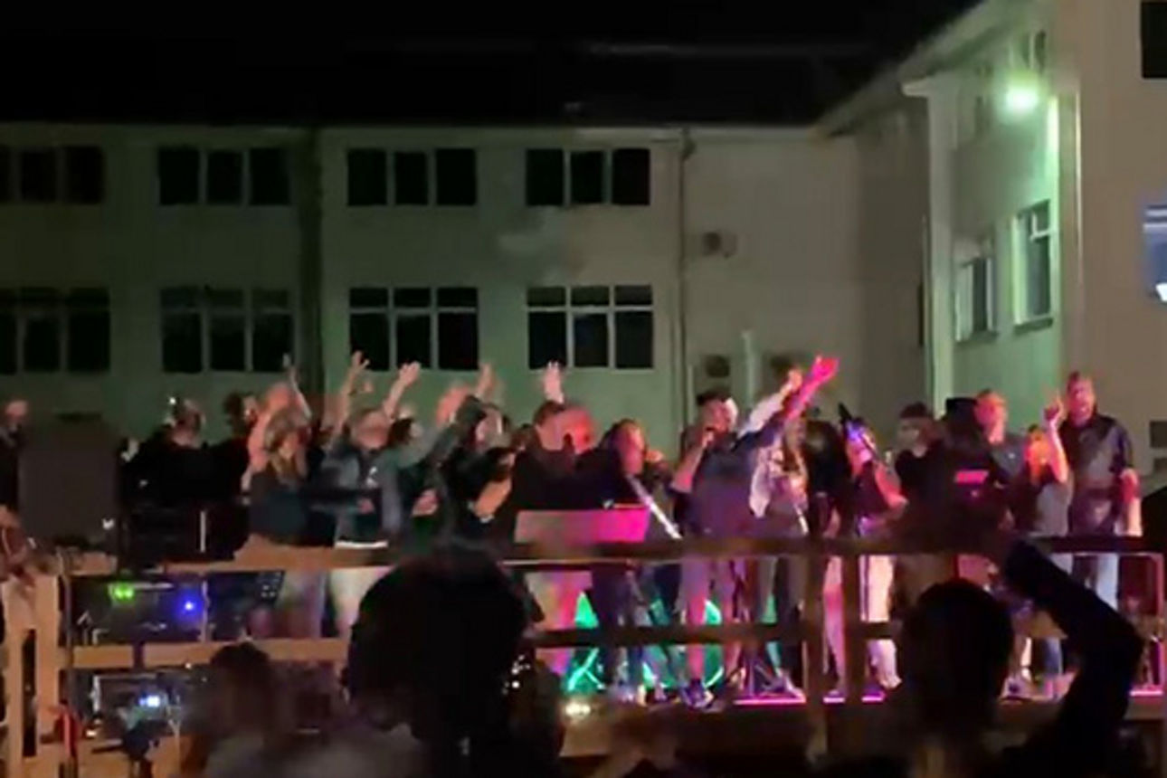 Viele Menschen stehen auf einer Bühne und singen.