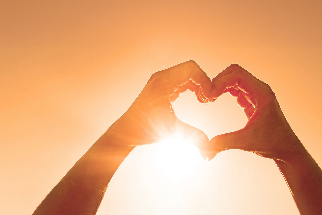 Zwei Hände sind vor der Sonne zu einem Herz geformt