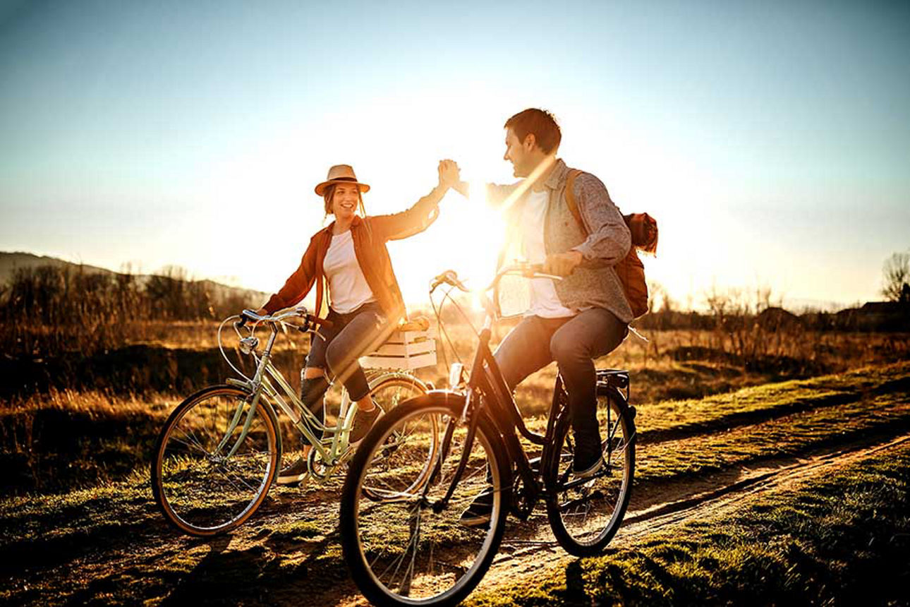 Couple driving on bicycle in nature, enjoying the sun
