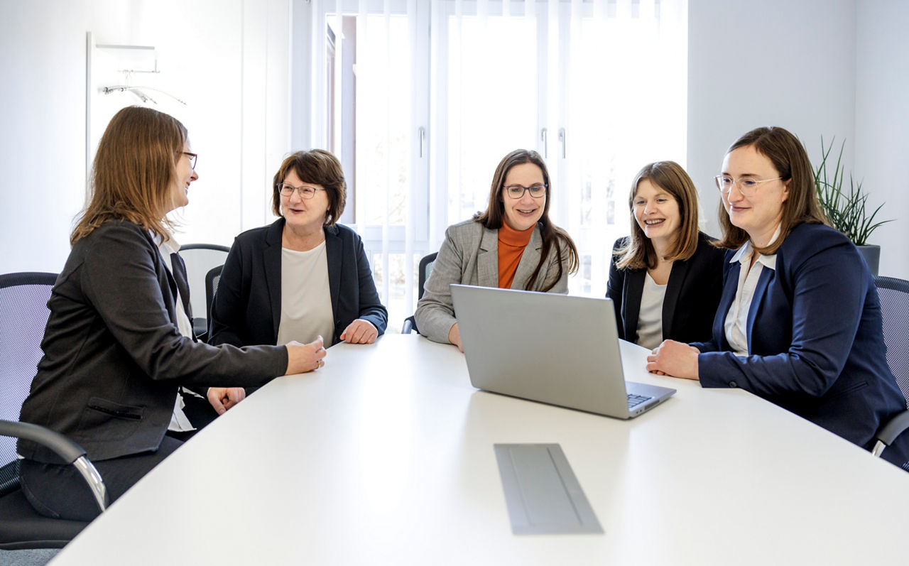 Fünf Beraterinnen sitzen gemeinsam am Tisch und reden miteinader.
