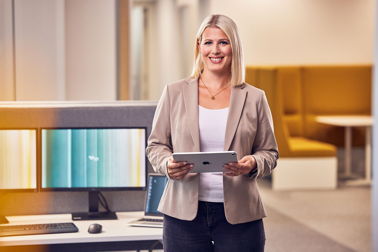 Frau hält Tablet in der Hand und lächelt in die Kamera