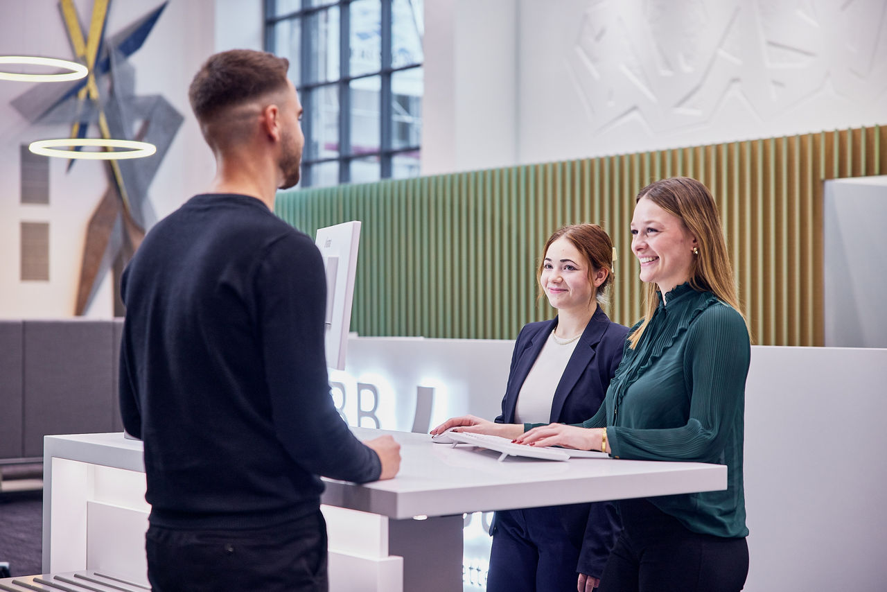 Zwei Bankmitarbeiterinnen stehen mit Kunde am Schalter