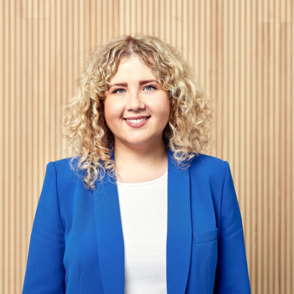 Natalie Anschiz mit blauem Blazer vor Holzwand