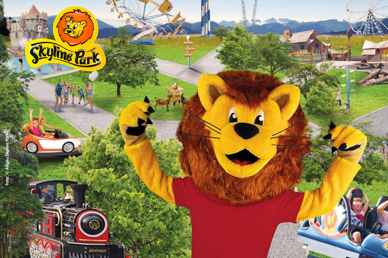 Ein Löwe als Maskottchen reckt die Arme in die Höhe, im Hintergrund sind Fahrgeschäfte des Skyline-Parks zu sehen