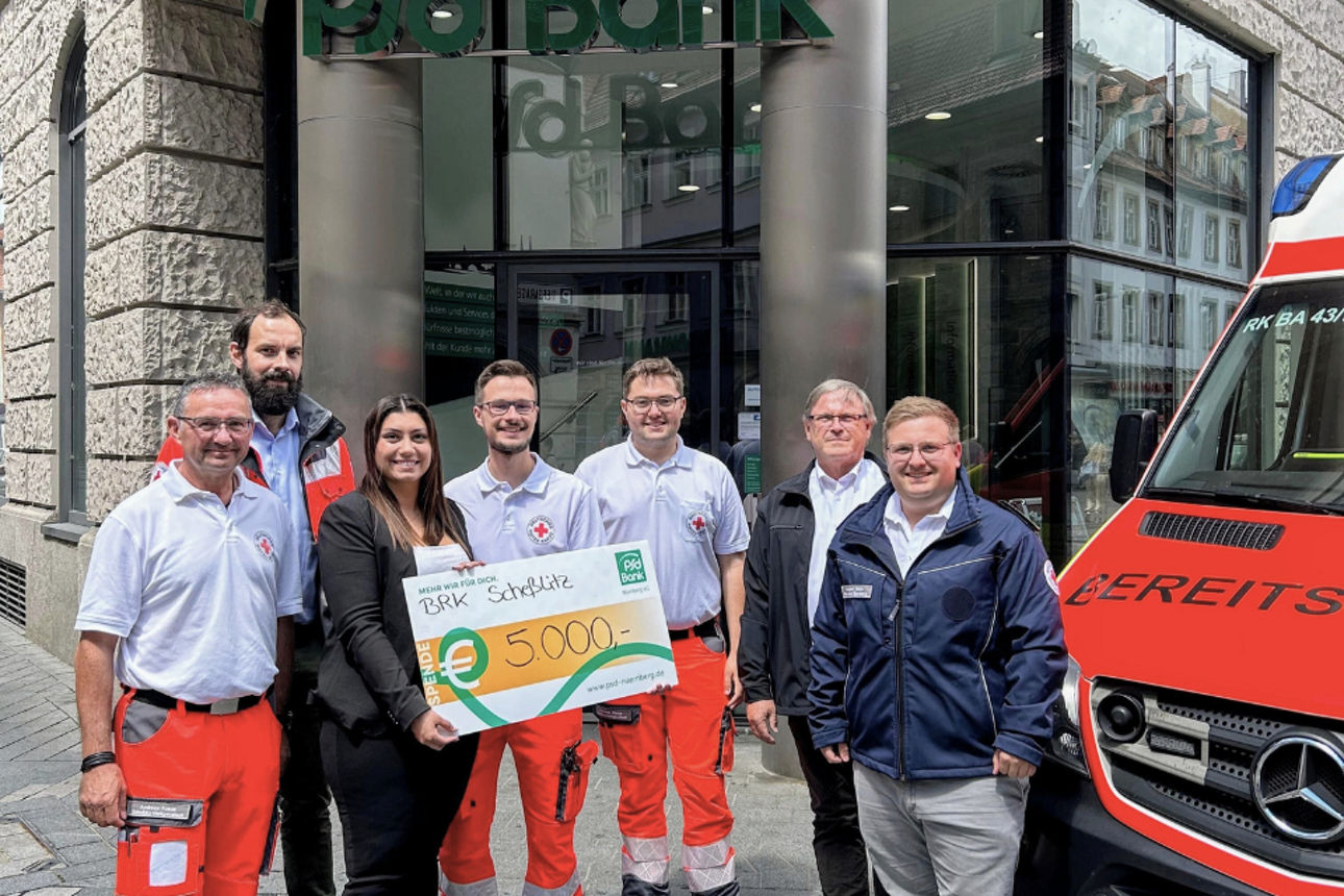 Eine Kollegin der PSD Bank Nürnberg übergibt einen Spendencheck an den BRK-Bereitsschaftsdienst.
