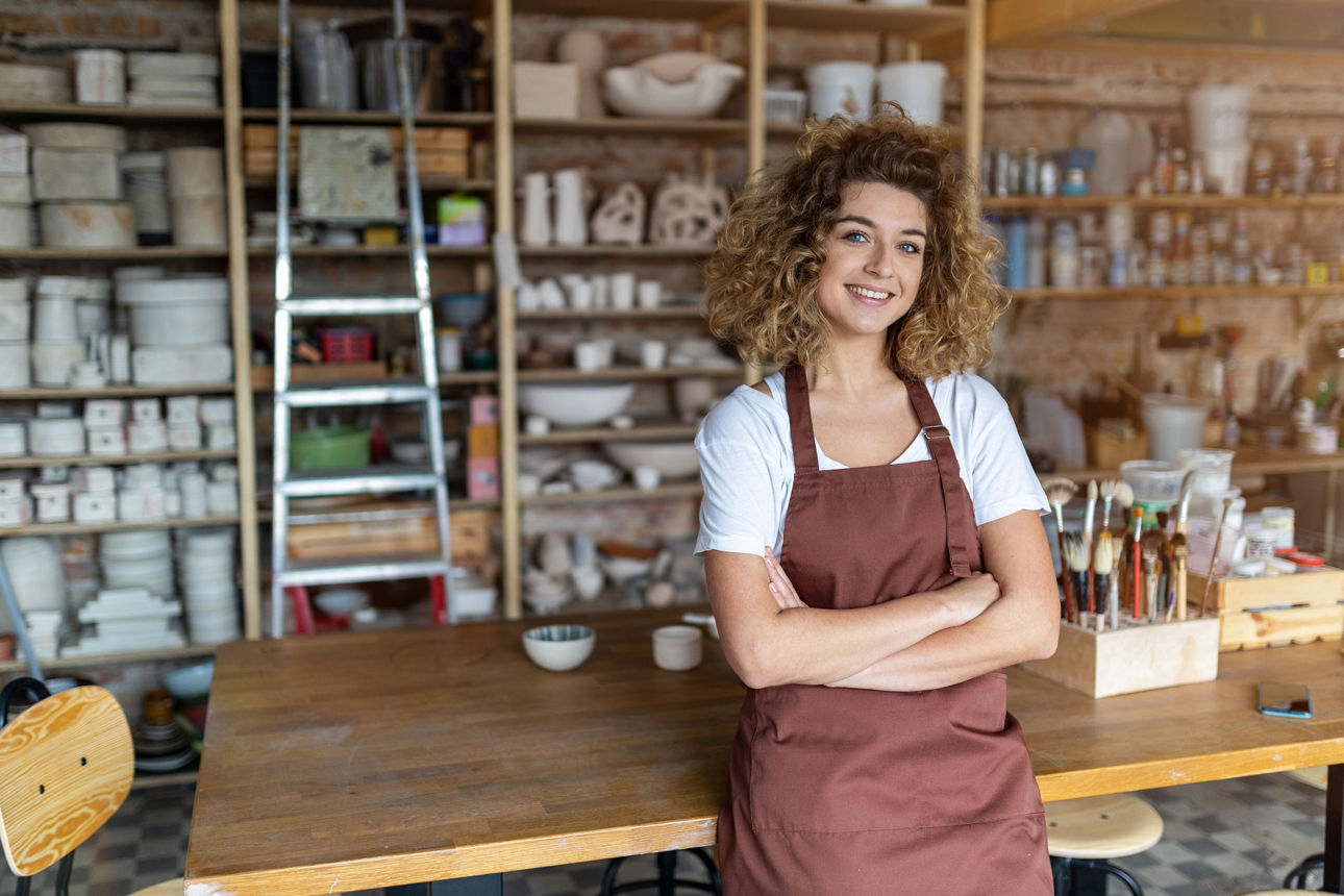 Junge Frau lehnt in einer Werkstatt an einem Werktisch