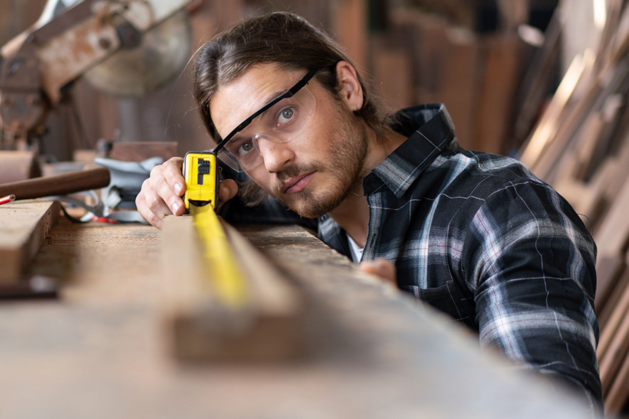 Junger Mann mit Brille und Maßband