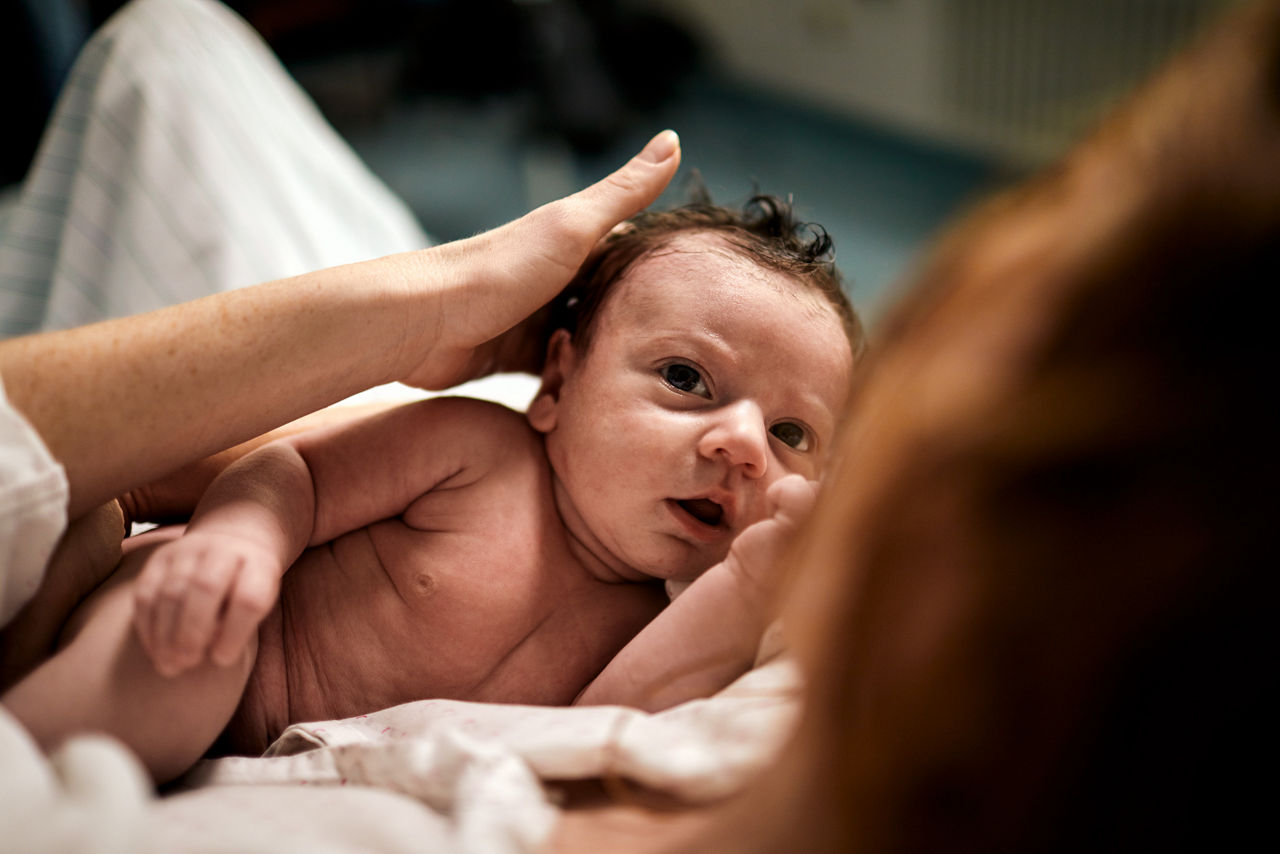 Baby nach der Geburt im Arm der Mutter 