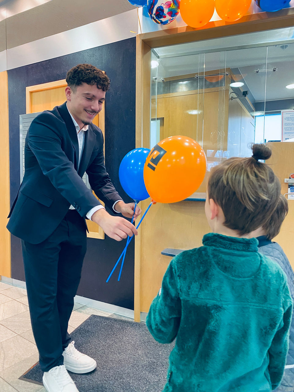 Auszubildender mit Luftballons vor Kindern