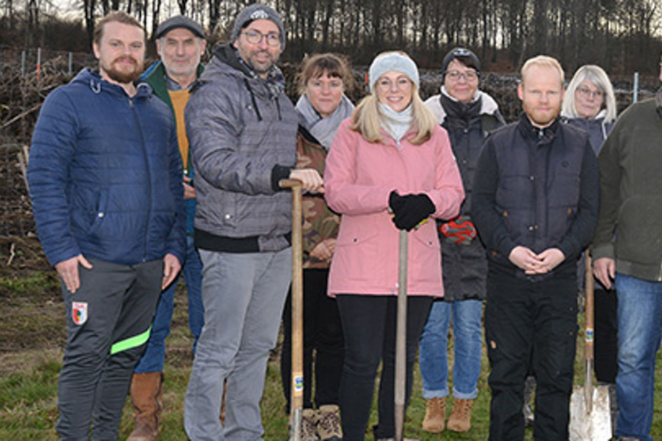Eine Menge Leute posieren für die Kamera auf einem Feld während eines Baumpflanzungscamps