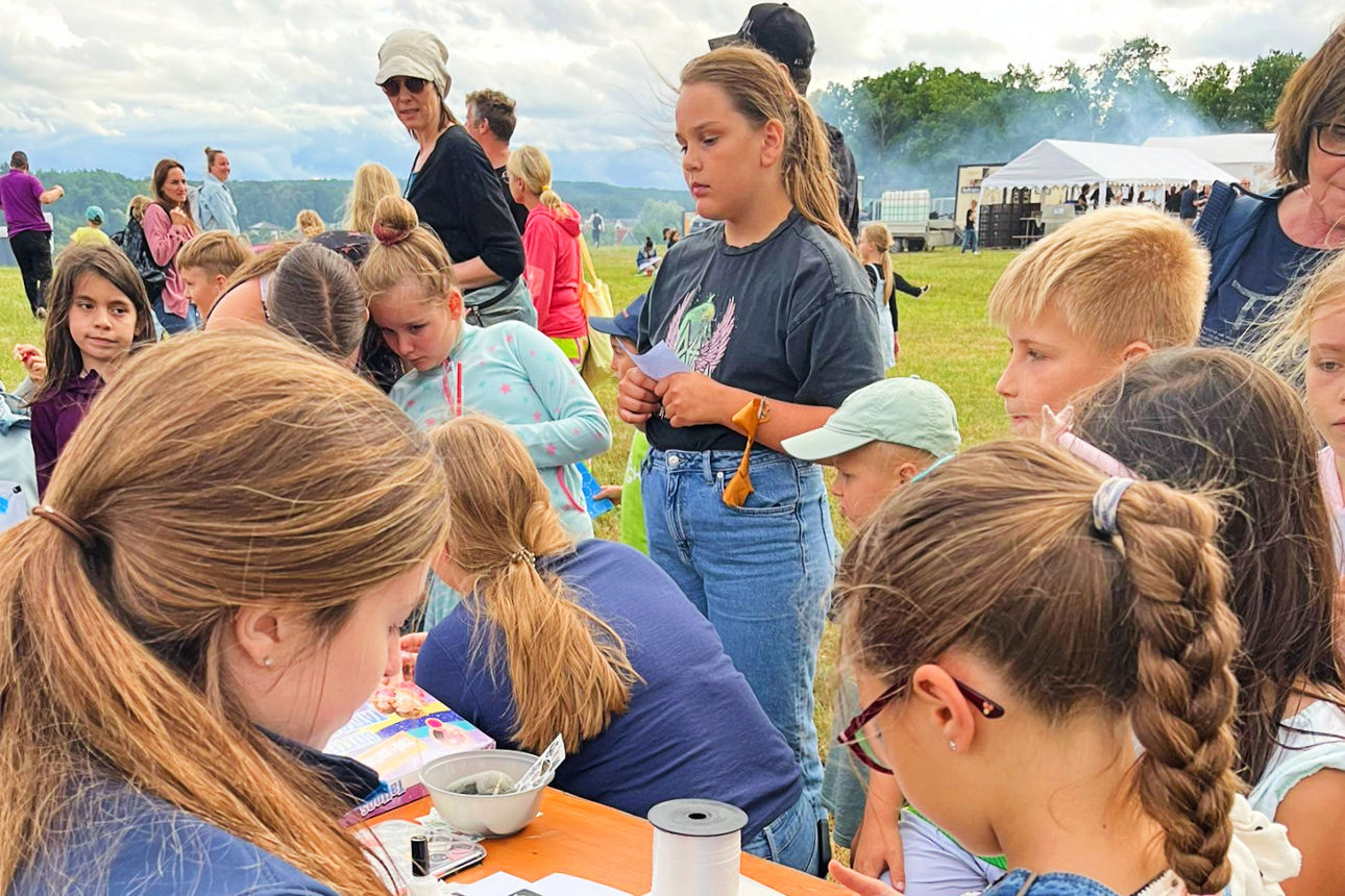 An einem Tisch wird ein kleines Kind von einer Bankmitarbeiterin geschminkt