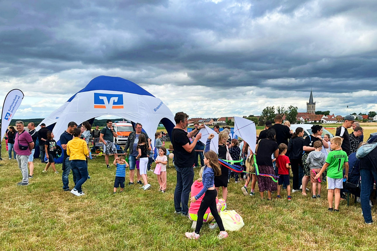 Menschen auf einer Wiese vor dem Raiffeisen-Kuppelzelt
