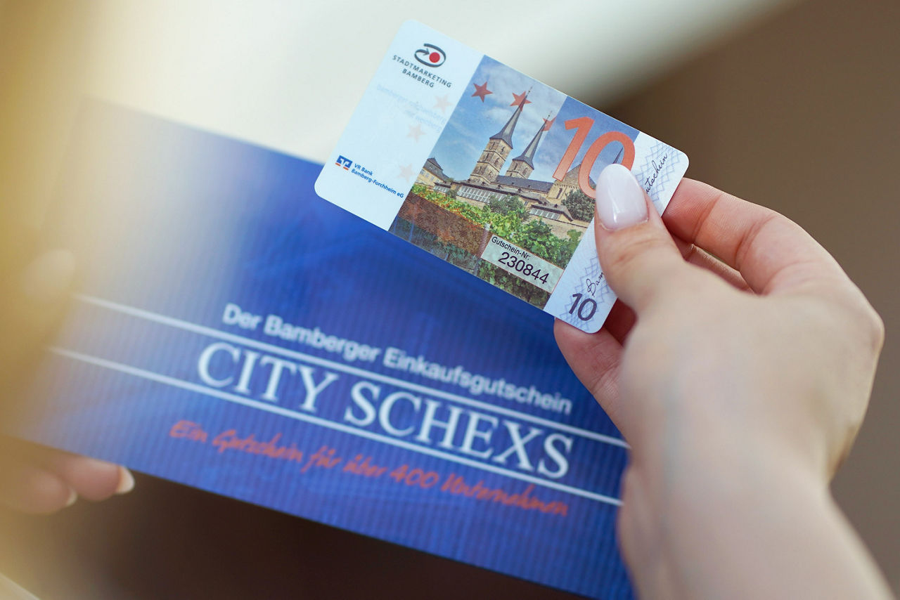 Frau hält Bamberger Einkaufsgutschein CITY SCHEXS in den Händen