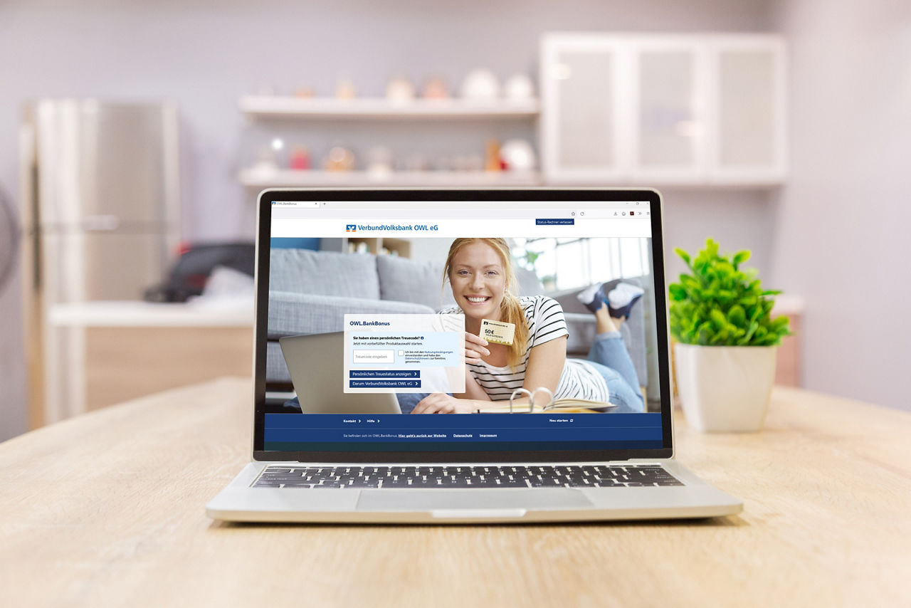 ein Laptop mit einer blonden Frau auf dem Bildschirm steht vor einem Laptop und lächelt