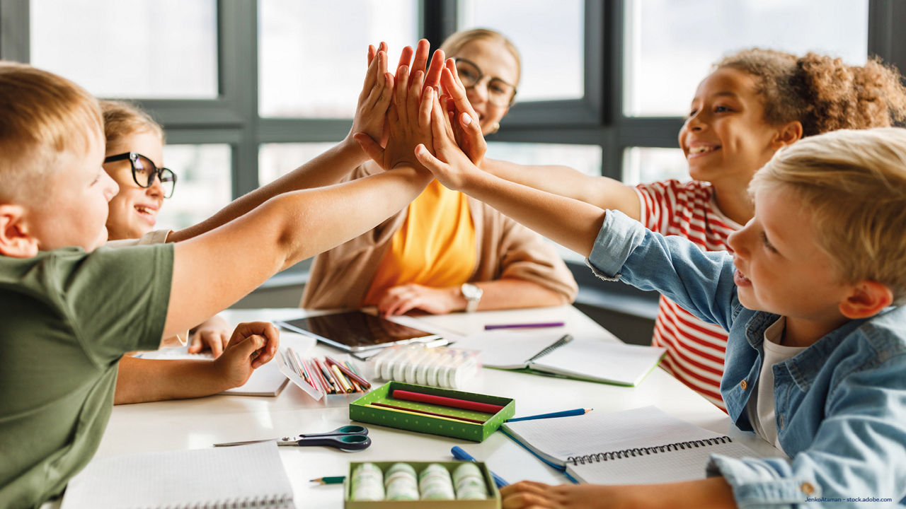 das Bild zeigt lachende Schüler am Tisch sitzend beim Lernen