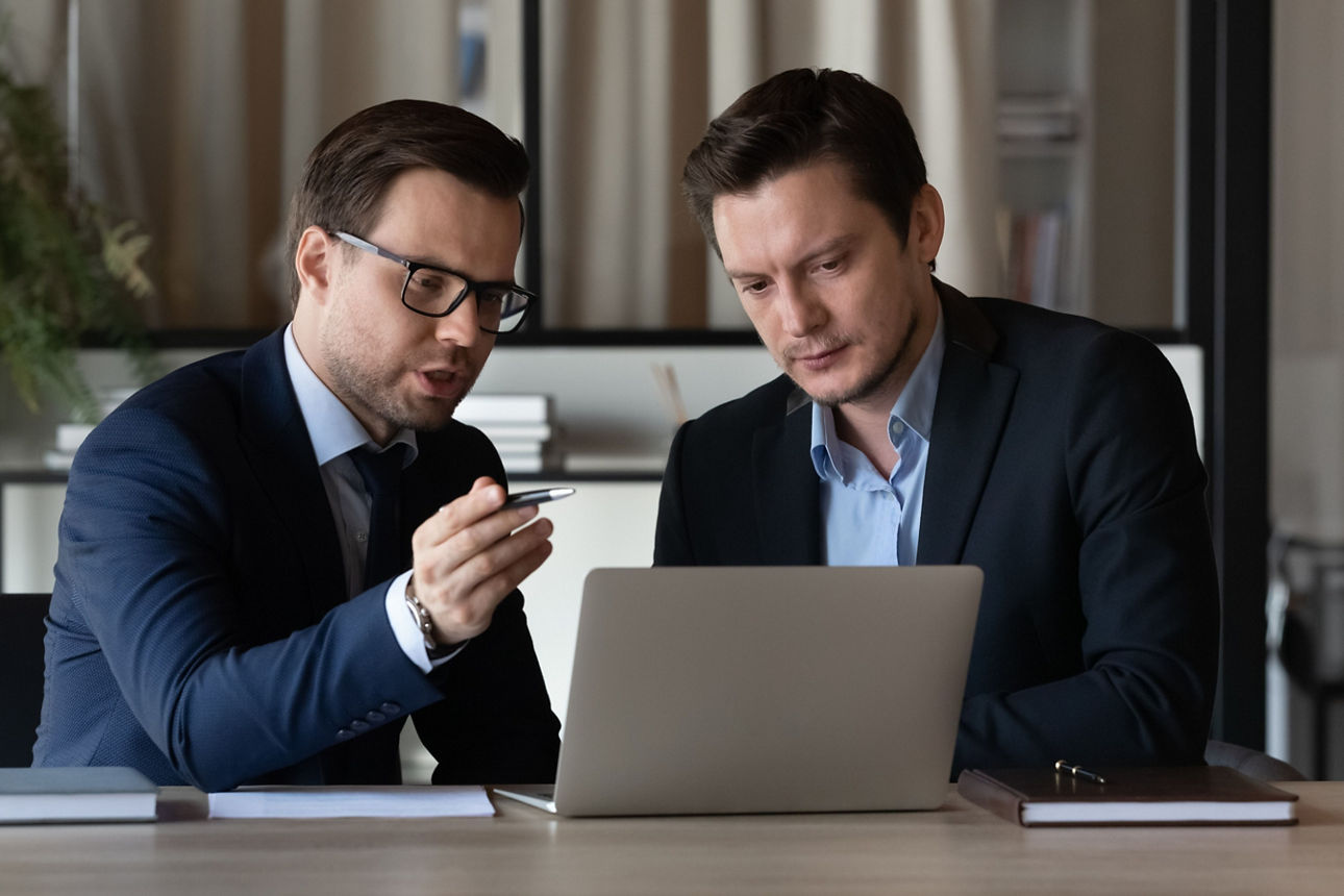 Bankberater im Gespräche mit einem Geschäftspartner schauen auf ein Notbook