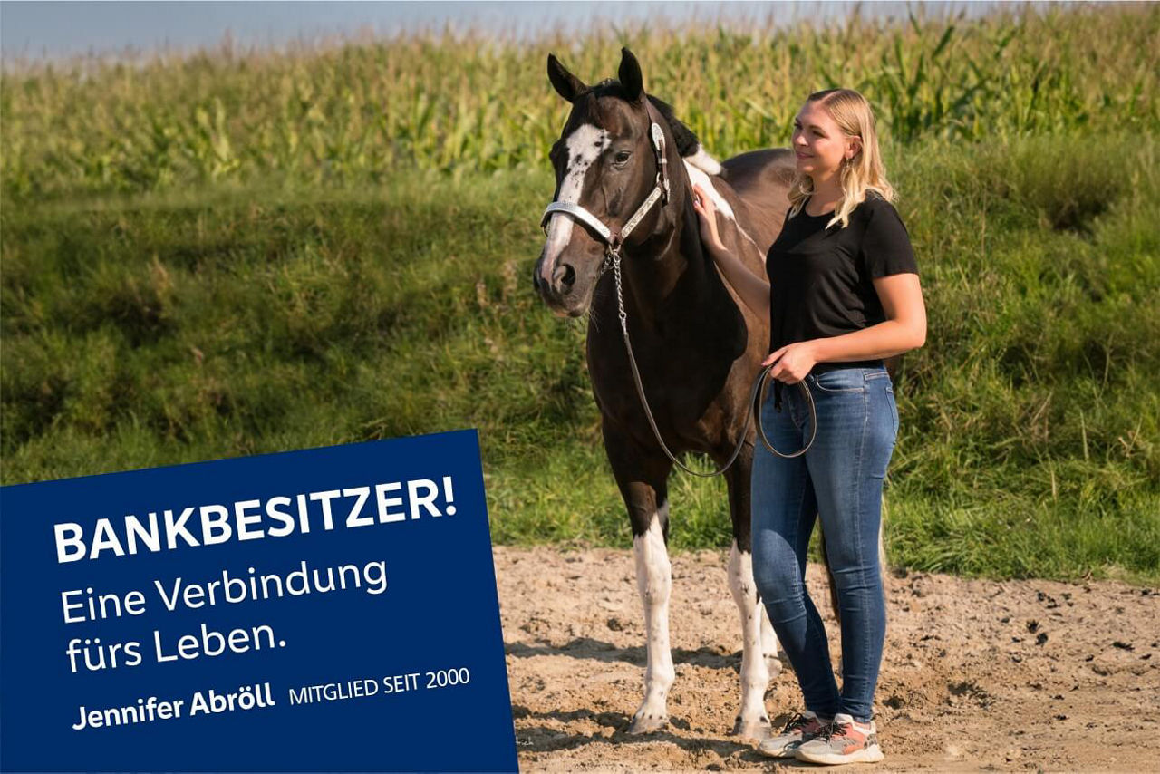 Jennifer Abröll steht neben ihrem Pferd im Freien an einem Sommertag. Im Hintgrund ist ein Feld zu sehen.