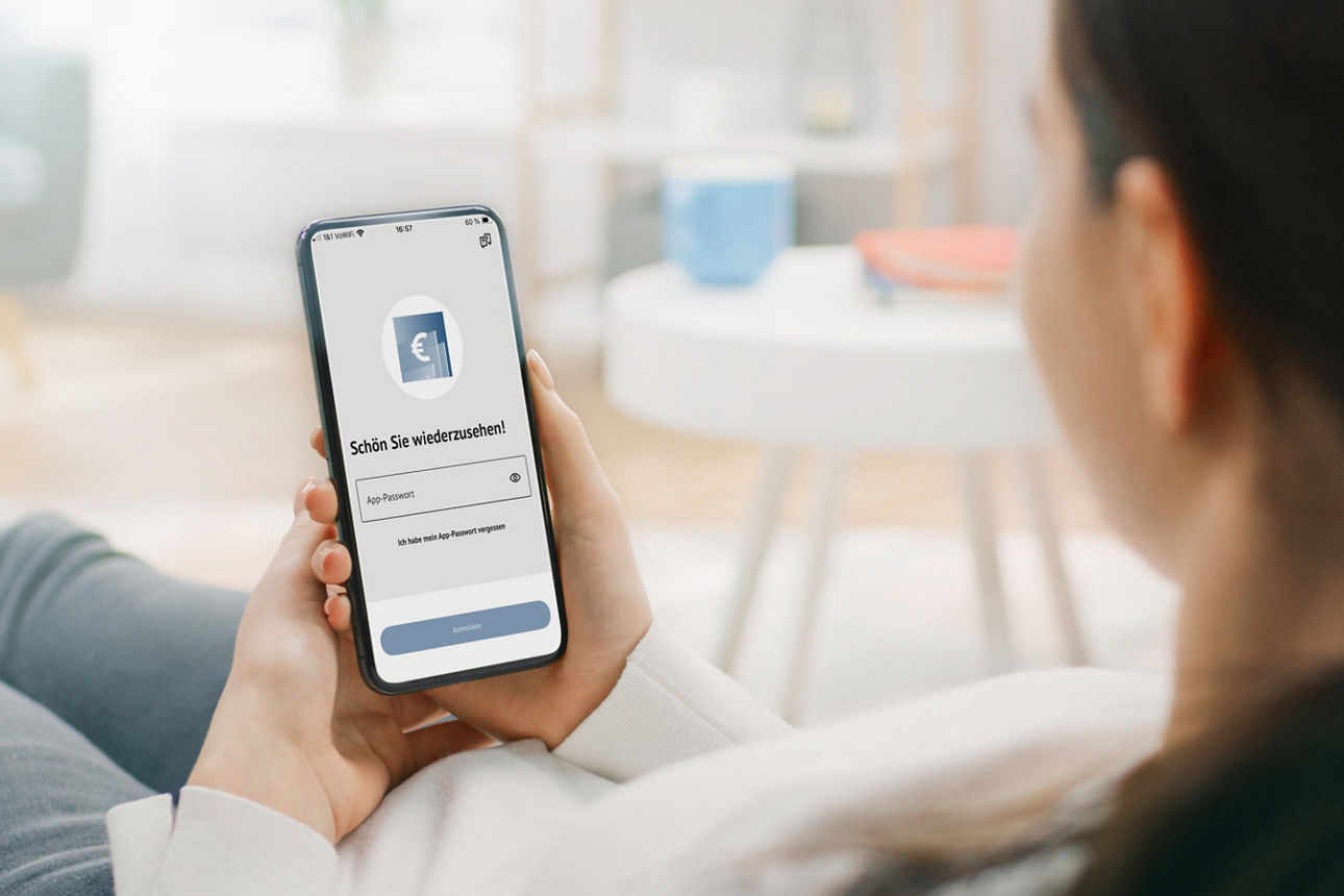 Eine Frau hält ein Handy in der Hand, auf dem die Login Seite der Banking App zu sehen ist.