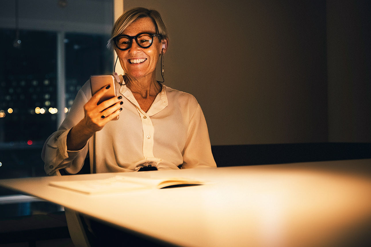 Frau an einem Tisch, die auf ihr Smartphone schaut