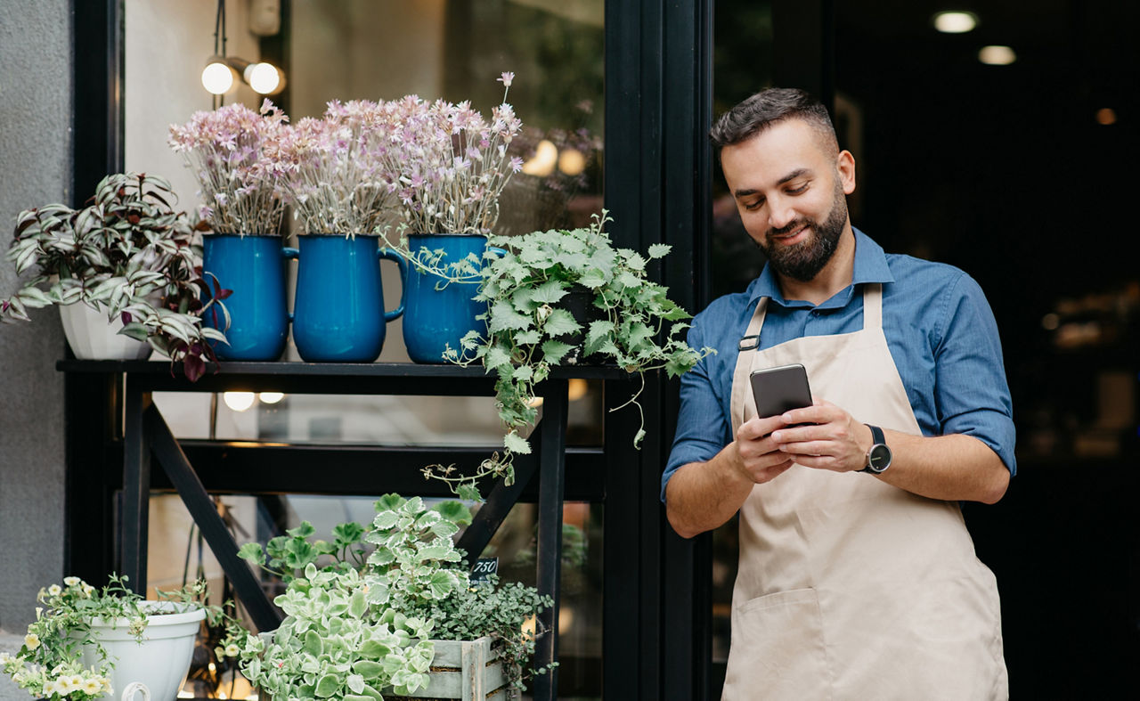 Inhaber eines Blumenladens, der auf sein Smartphone schaut