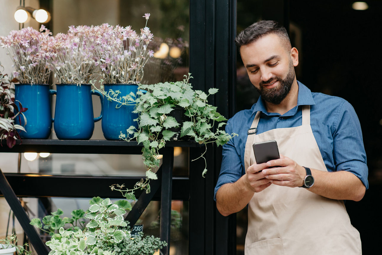 Inhaber eines Blumenladens, der auf sein Smartphone schaut