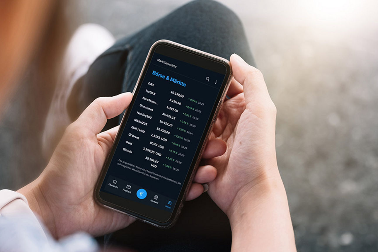 Ein Mann hält sein Handy mit der Banking App in der Hand und schaut sein Depot an.
