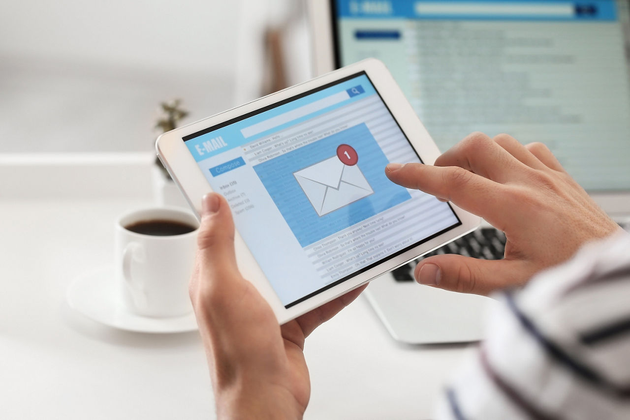 Zwei Hände halten ein Tablet in der Hand mit einem Umschlag auf dem Display