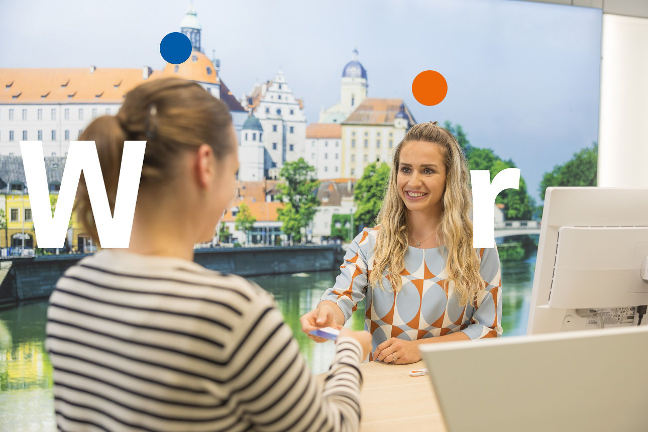 Zwei junge Damen stehend lächelnd an einem Service-Desk.