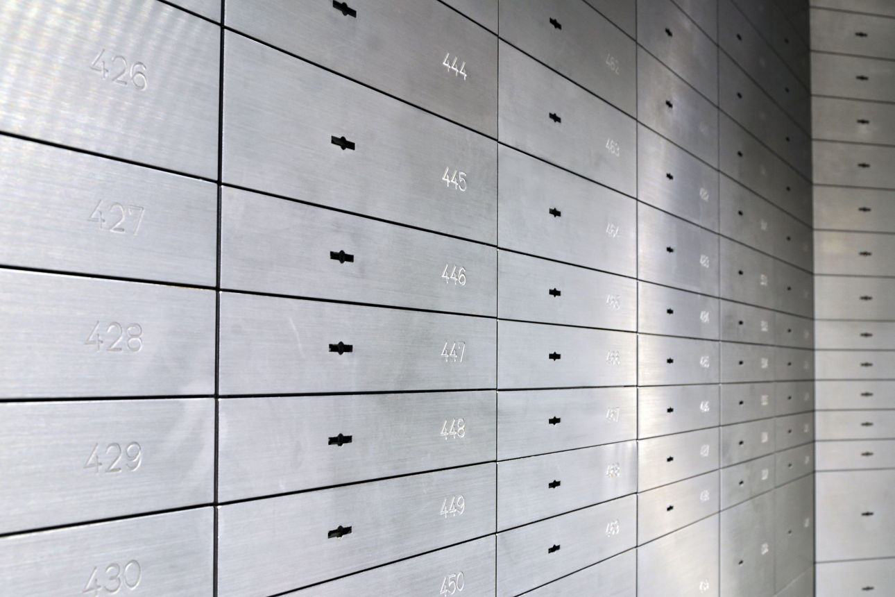 Reihe von nummerierten Bankschließfächern aus Metall in einem Tresorraum.