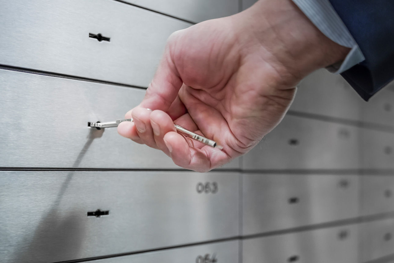 Bankschließfach wird mit einem Schlüssel in der Hand geöffnet.