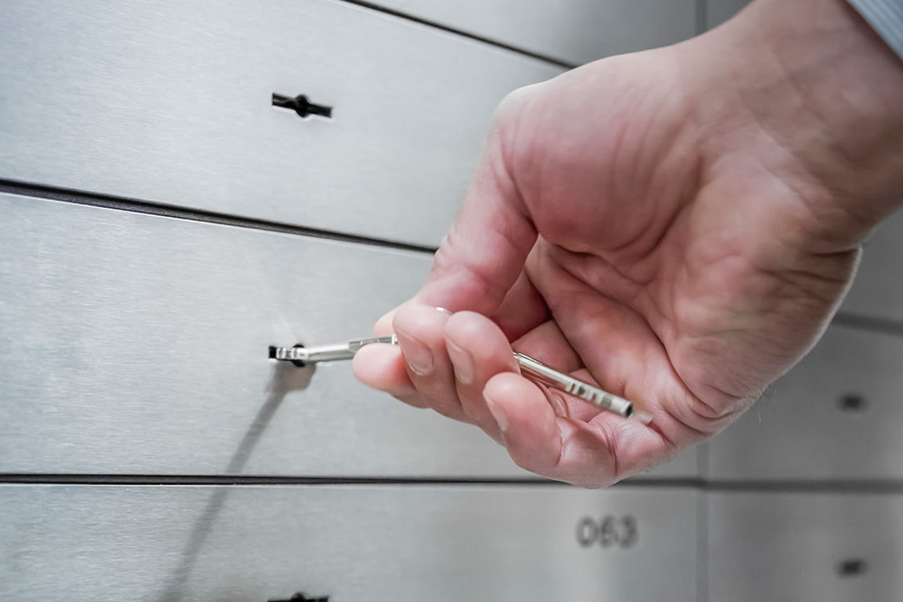 Bankschließfach wird mit einem Schlüssel in der Hand geöffnet.